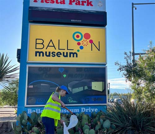 Cleaning up litter in front of the Balloon Museum sign