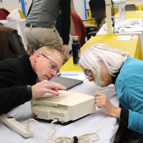 Two people working to fix an electronic device